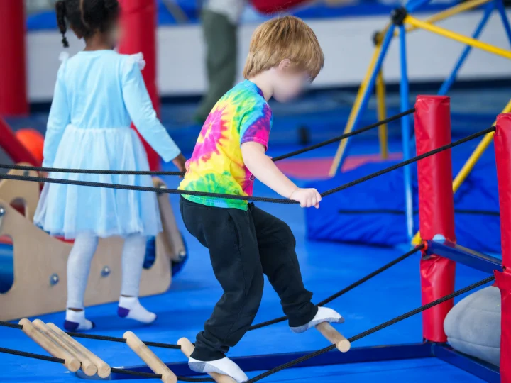 A boy crossing a rope bridge at a sensory gym
